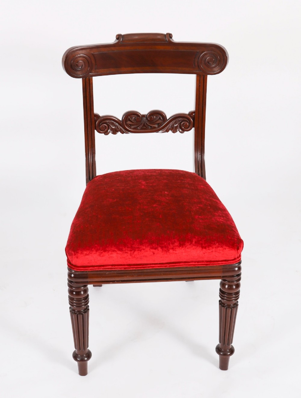A set of ten Regency flame mahogany dining chairs with carved scroll backrails, turned fluted front legs, and red velvet seats. View X