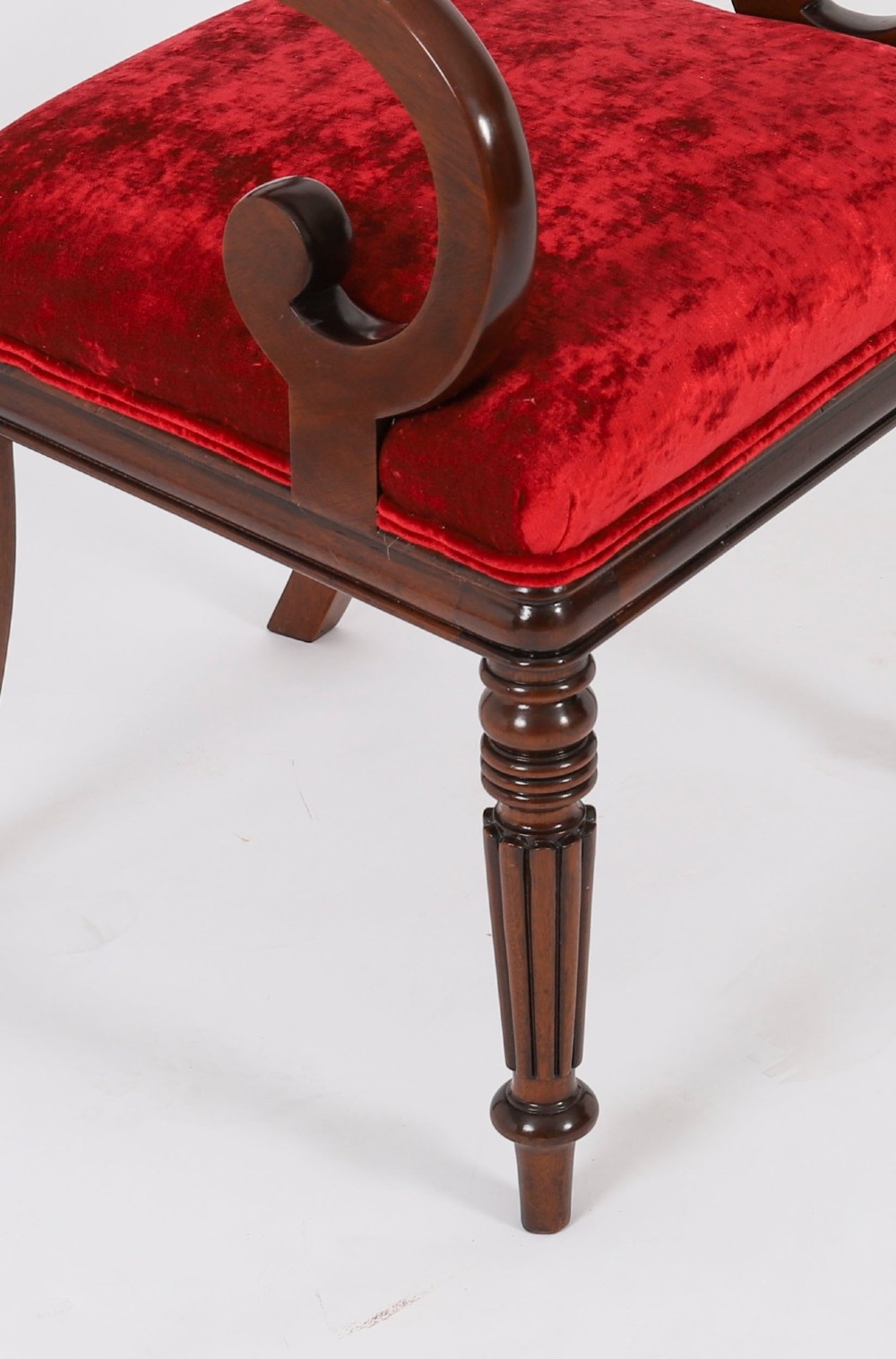 A set of ten Regency flame mahogany dining chairs with carved scroll backrails, turned fluted front legs, and red velvet seats. View XIII