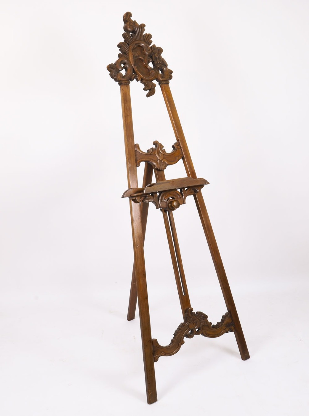 A 19th-century carved walnut artist easel featuring an ornate Rococo Revival scrollwork crest and an adjustable ledge on a tripod frame. View IV