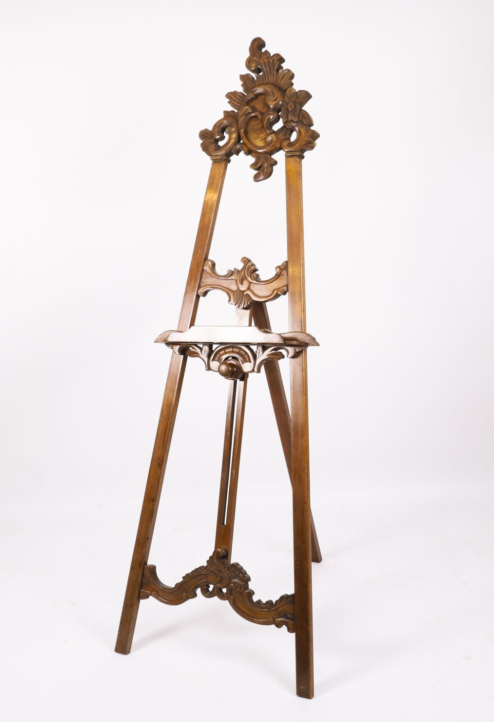 A 19th-century carved walnut artist easel featuring an ornate Rococo Revival scrollwork crest and an adjustable ledge on a tripod frame. View X