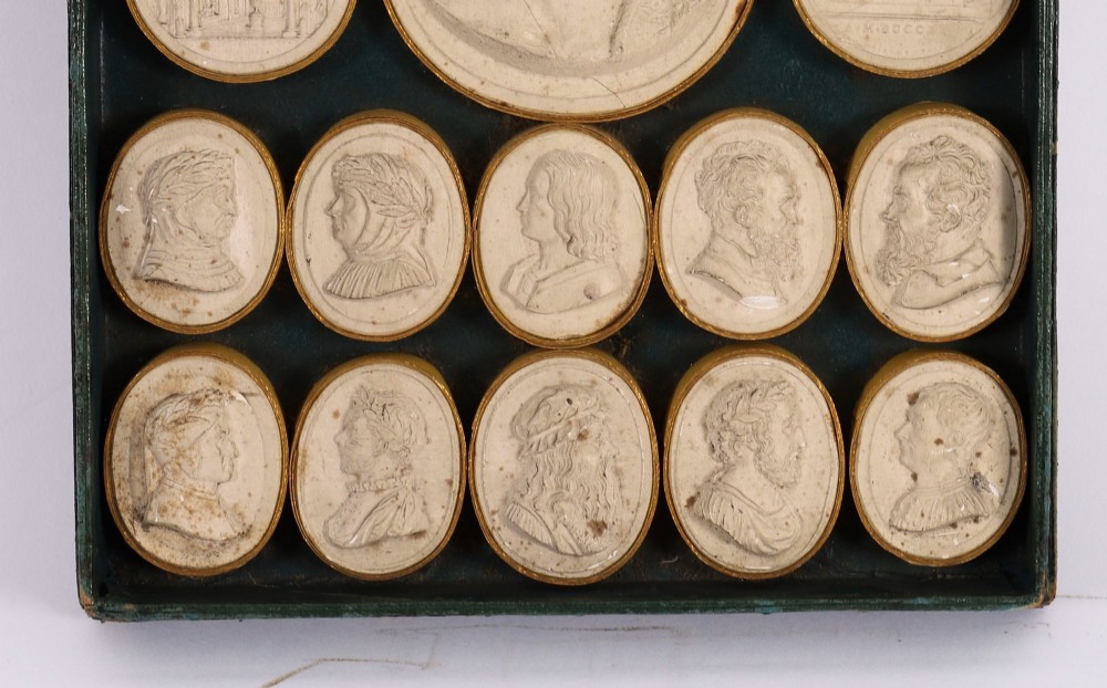 An 18th-century set of cream plaster intaglio medallions arranged in a fitted green tray beside a handwritten manuscript index lid. View VI