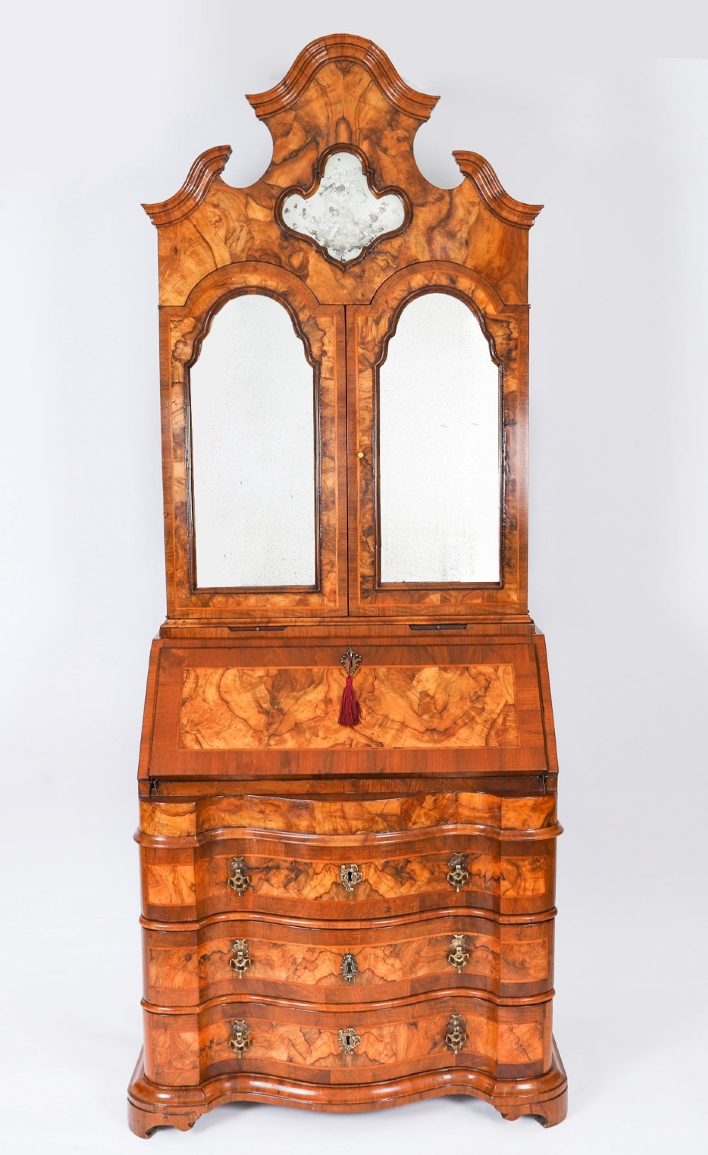 An 18th-century Venetian burr walnut bureau bookcase featuring a shaped top pediment with mirrored inset, twin mirrored cabinet doors, a slant-front writing slope, and three serpentine drawers. View II