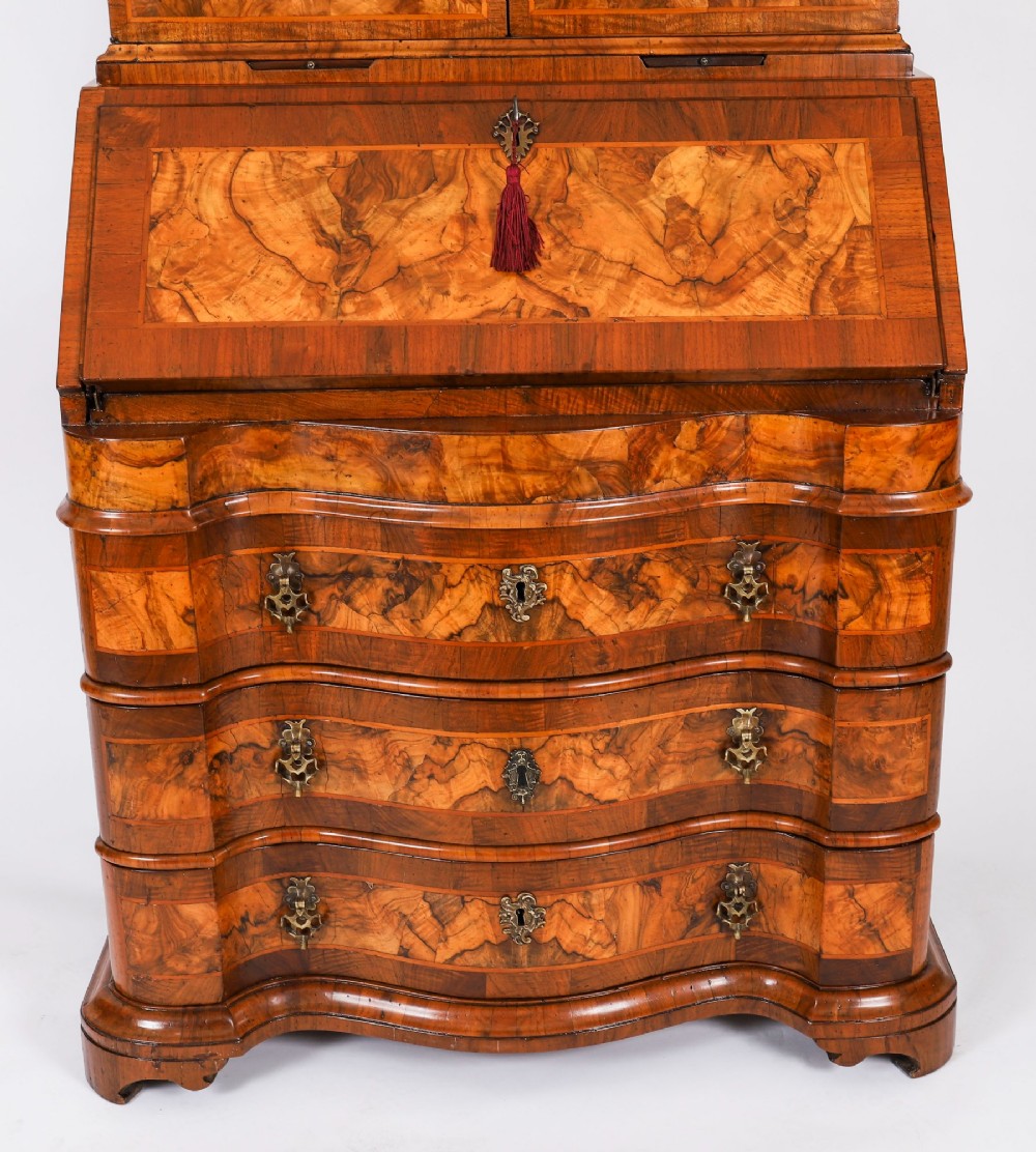 An 18th-century Venetian burr walnut bureau bookcase featuring a shaped top pediment with mirrored inset, twin mirrored cabinet doors, a slant-front writing slope, and three serpentine drawers. View V