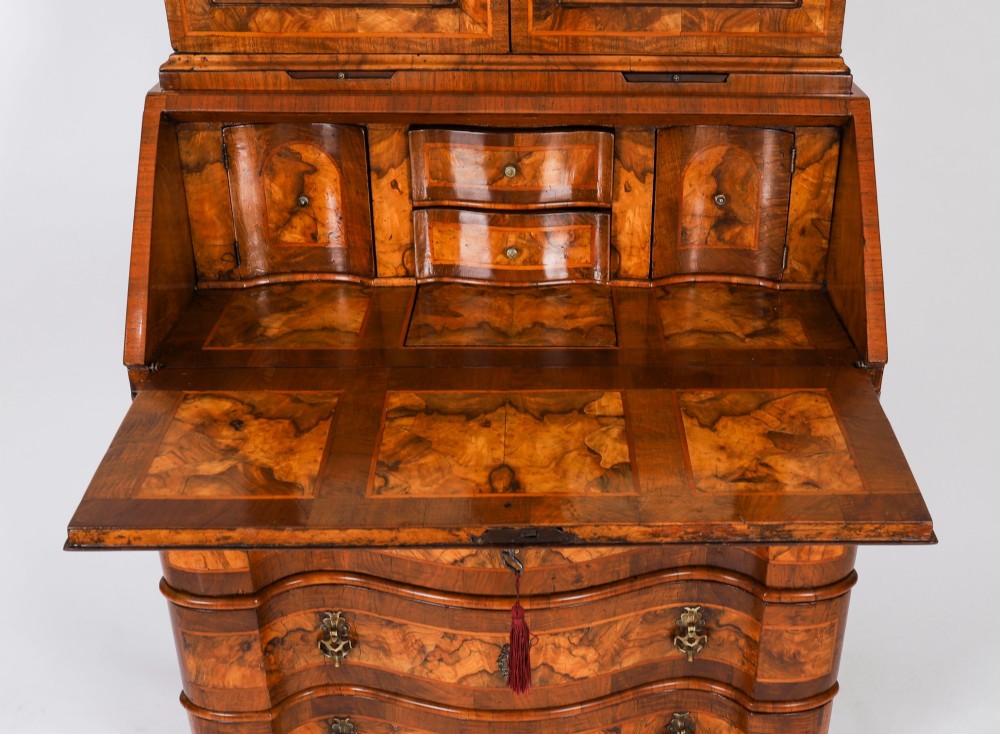 An 18th-century Venetian burr walnut bureau bookcase featuring a shaped top pediment with mirrored inset, twin mirrored cabinet doors, a slant-front writing slope, and three serpentine drawers. View VIII
