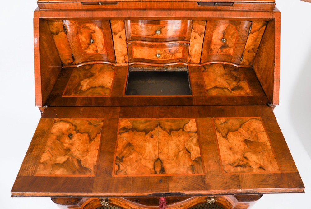 An 18th-century Venetian burr walnut bureau bookcase featuring a shaped top pediment with mirrored inset, twin mirrored cabinet doors, a slant-front writing slope, and three serpentine drawers. View X