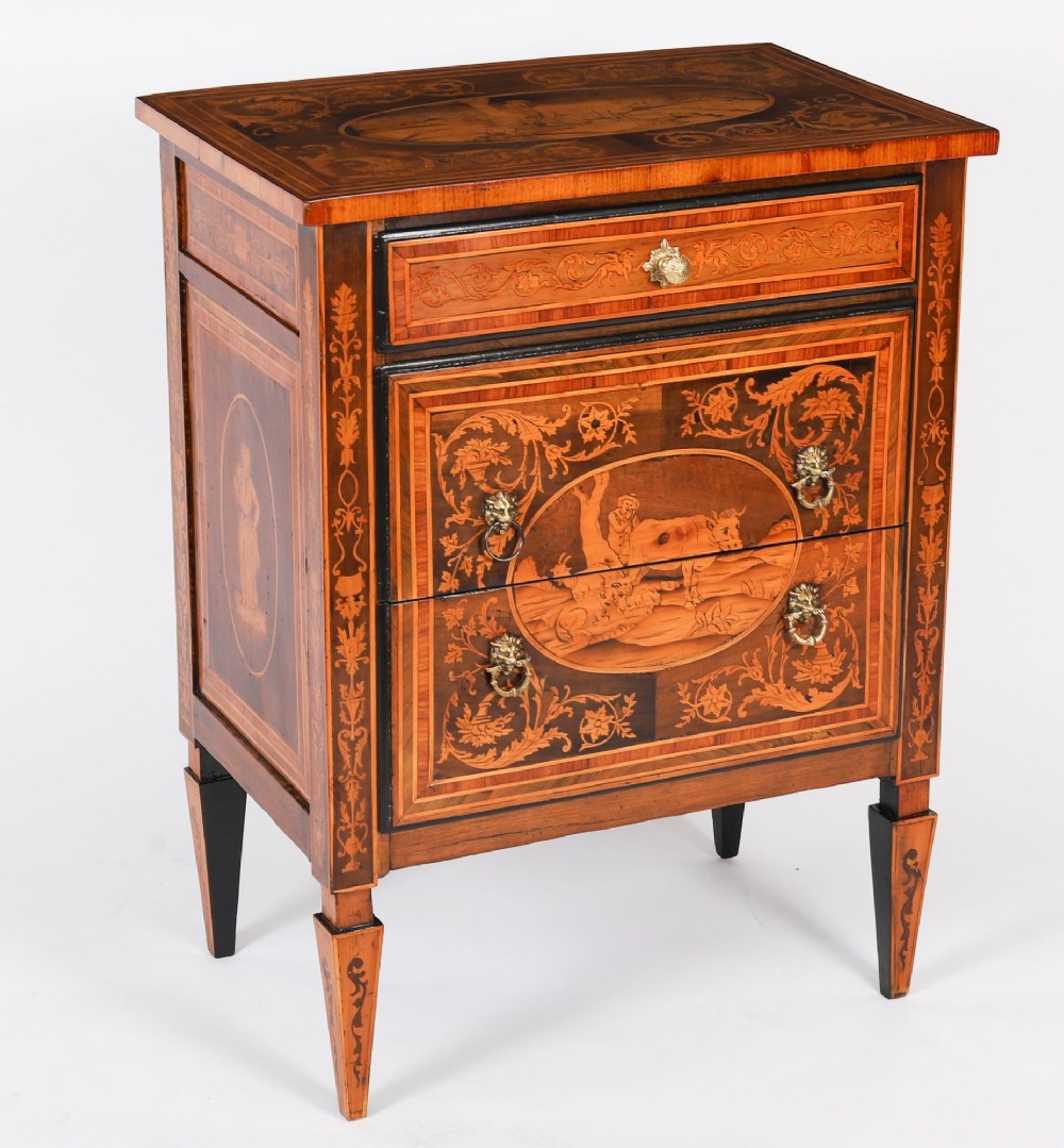 An 18th-century Italian Neoclassical walnut commodino featuring intricate foliate and pictorial marquetry inlay, three drawers with lion head ring pulls, and square tapered legs.