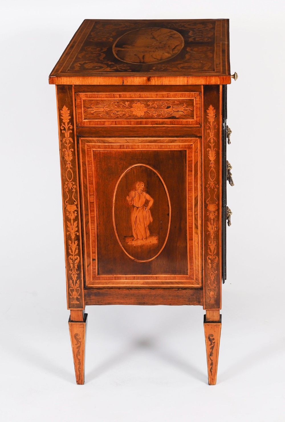 An 18th-century Italian Neoclassical walnut commodino featuring intricate foliate and pictorial marquetry inlay, three drawers with lion head ring pulls, and square tapered legs. View IX