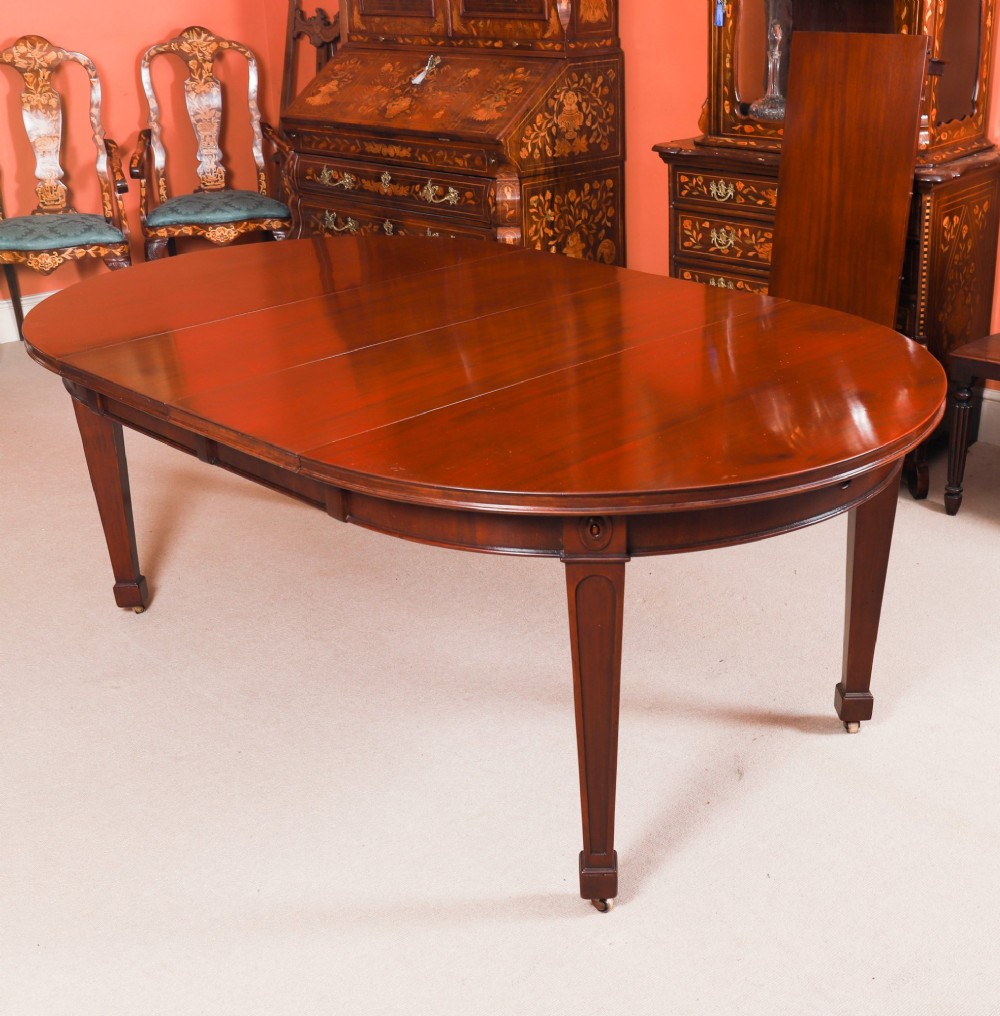 An antique Victorian oval extending dining table crafted from flame mahogany with tapered legs on brass castors. View V