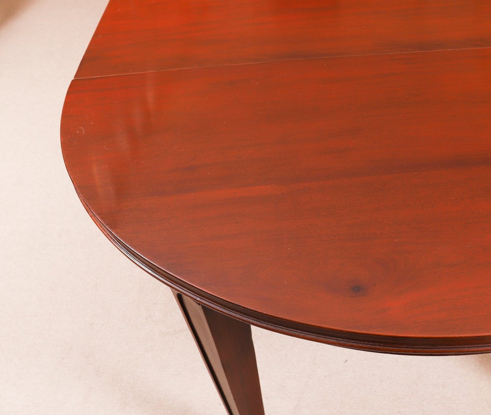 An antique Victorian oval extending dining table crafted from flame mahogany with tapered legs on brass castors. View XIII