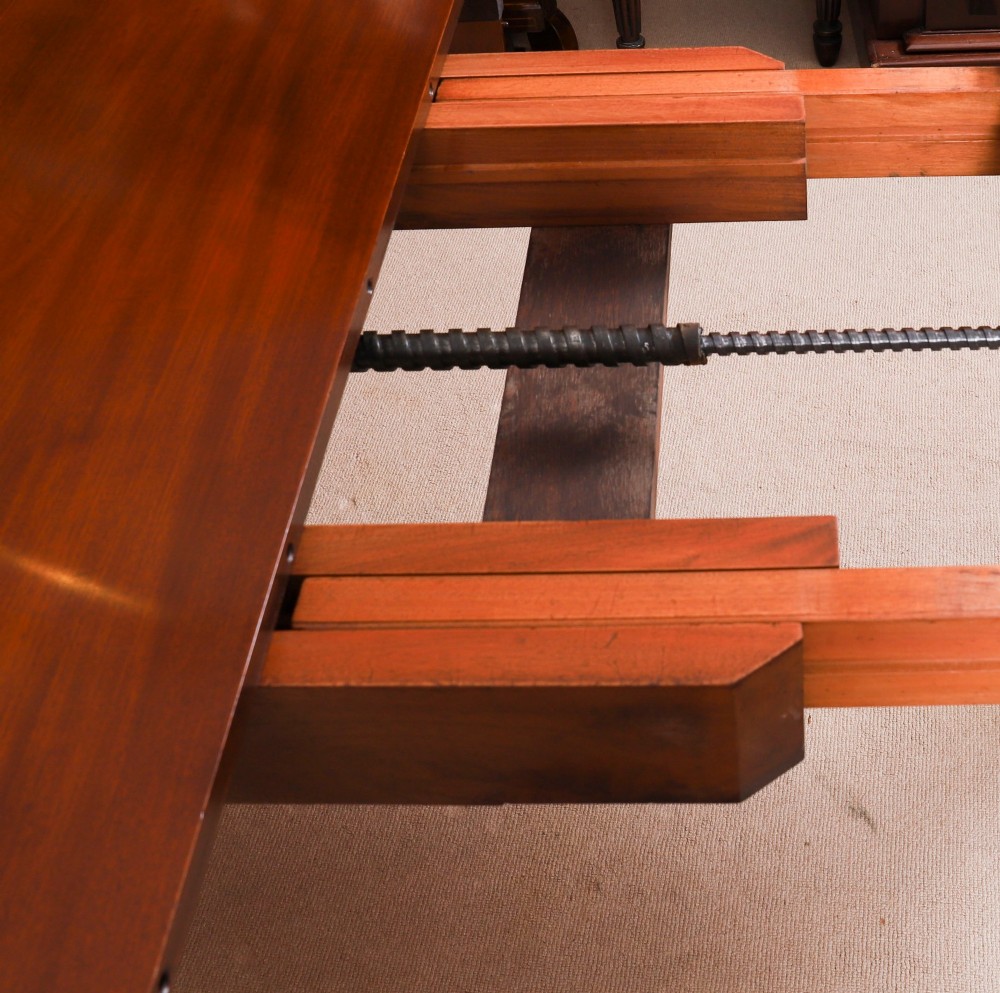 An antique Victorian oval extending dining table crafted from flame mahogany with tapered legs on brass castors. View XV