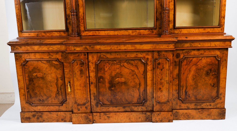 A mid-19th-century Victorian burr walnut breakfront bookcase featuring three upper glazed doors, turned pilasters, and three lower panelled cupboard doors. View III