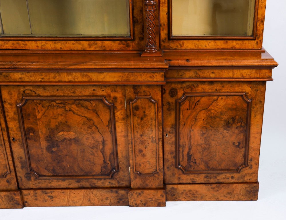 A mid-19th-century Victorian burr walnut breakfront bookcase featuring three upper glazed doors, turned pilasters, and three lower panelled cupboard doors. View IV