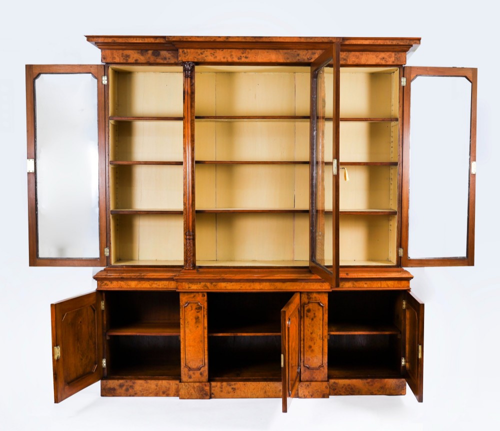 A mid-19th-century Victorian burr walnut breakfront bookcase featuring three upper glazed doors, turned pilasters, and three lower panelled cupboard doors. View IX