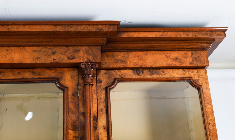 A mid-19th-century Victorian burr walnut breakfront bookcase featuring three upper glazed doors, turned pilasters, and three lower panelled cupboard doors. View XII