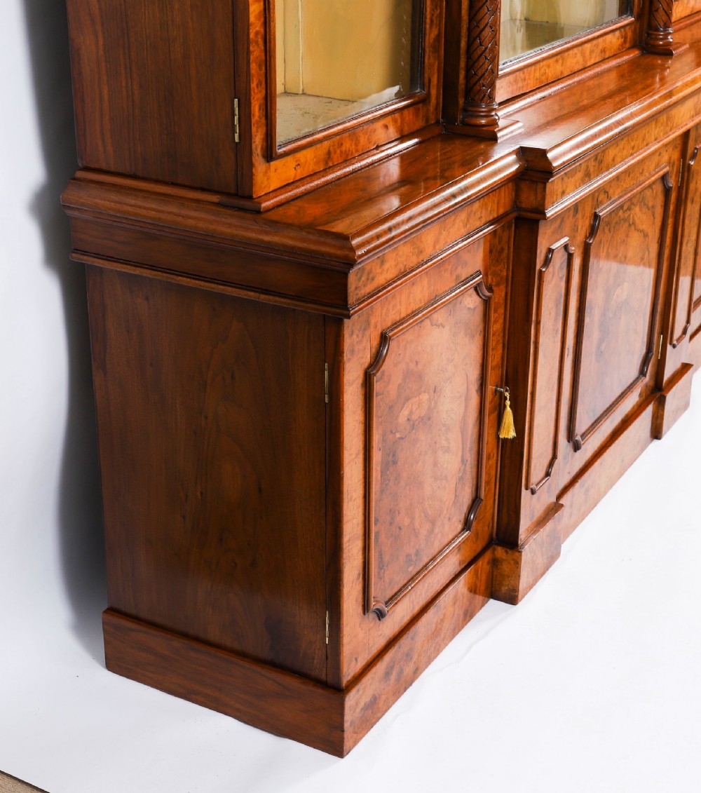 A mid-19th-century Victorian burr walnut breakfront bookcase featuring three upper glazed doors, turned pilasters, and three lower panelled cupboard doors. View XIII