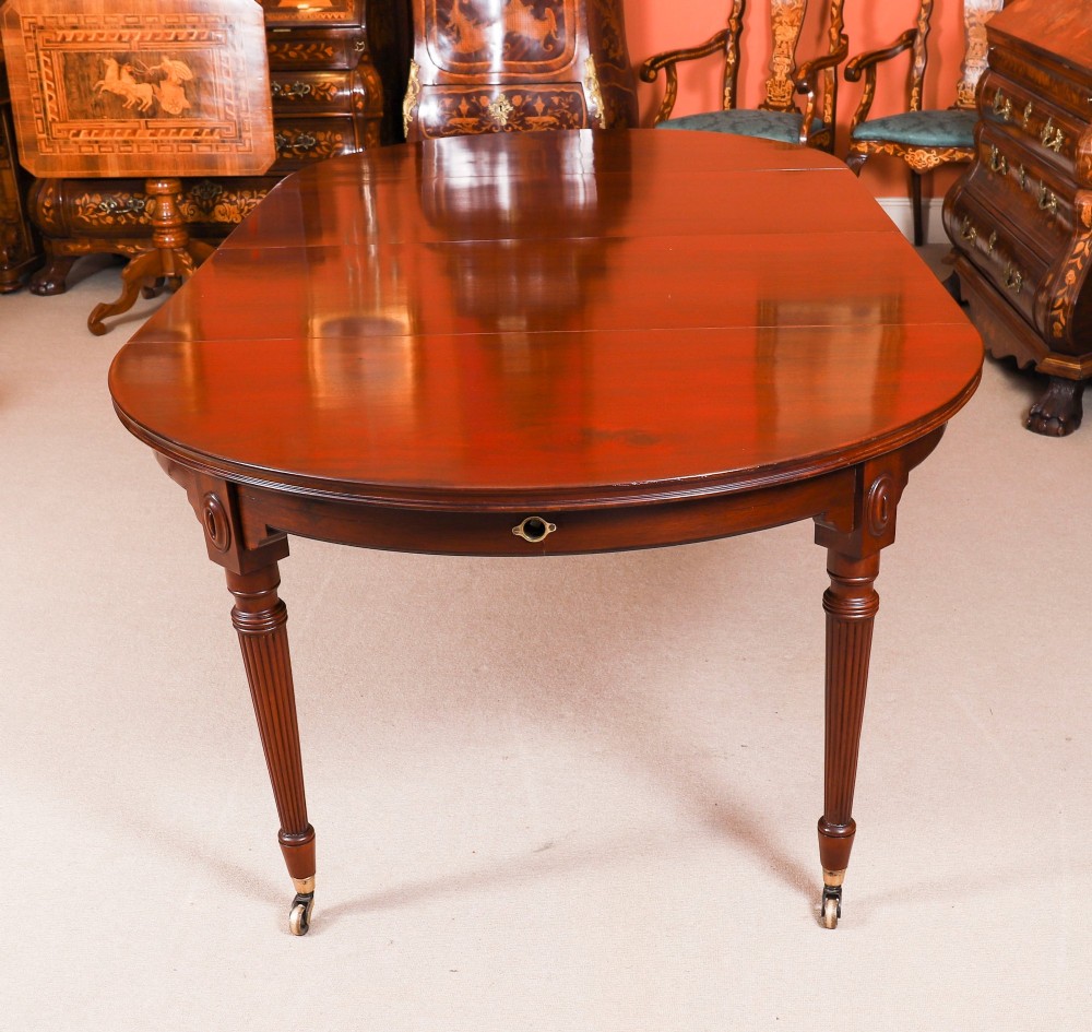 An antique Victorian flame mahogany extending dining table with fluted tapering legs set on brass castors. View IV