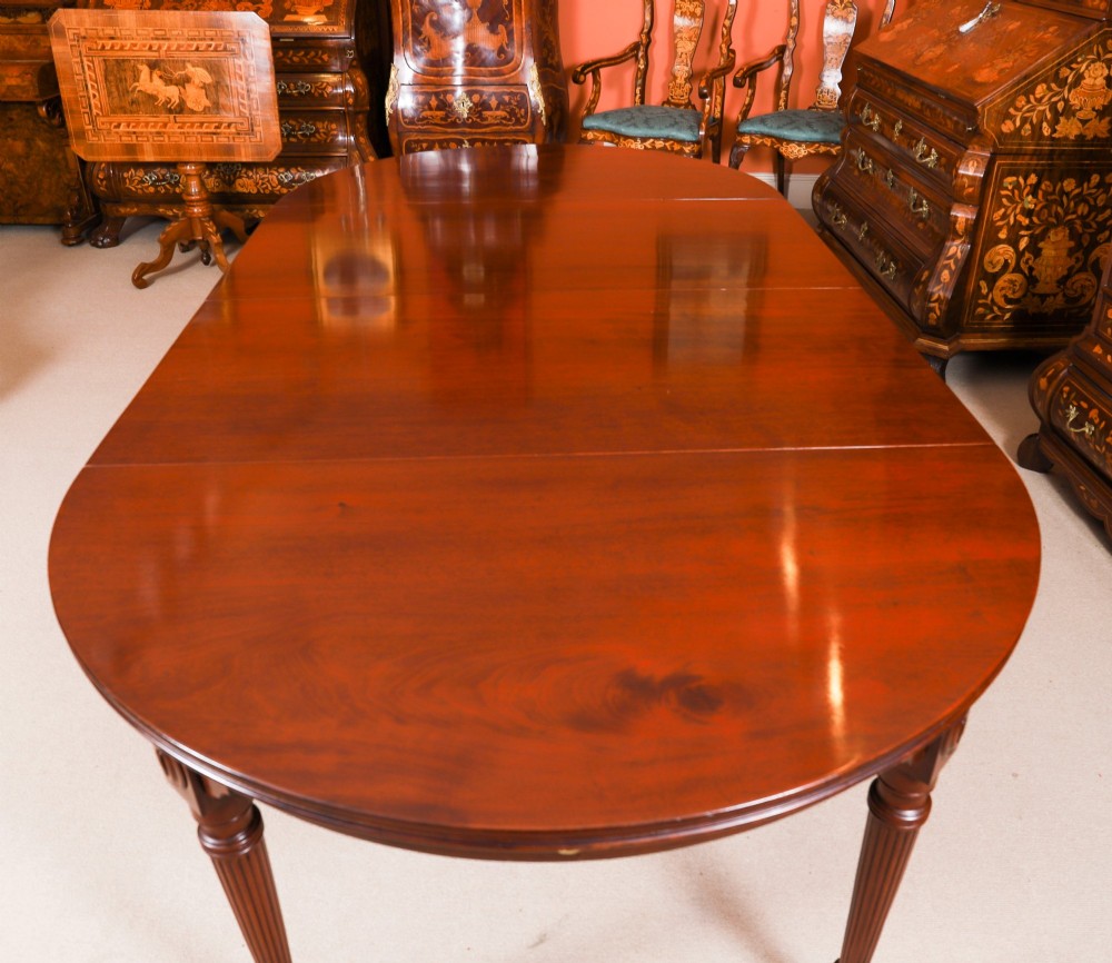 An antique Victorian flame mahogany extending dining table with fluted tapering legs set on brass castors. View V