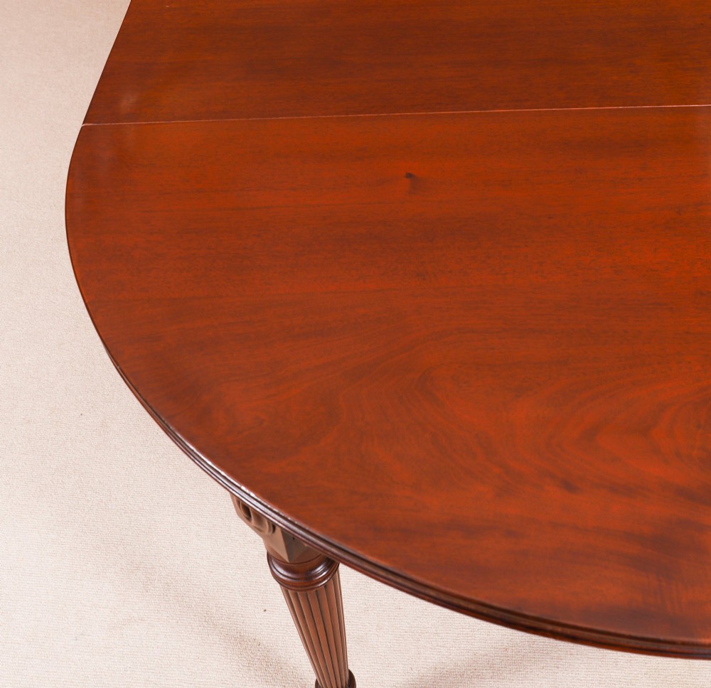 An antique Victorian flame mahogany extending dining table with fluted tapering legs set on brass castors. View VII