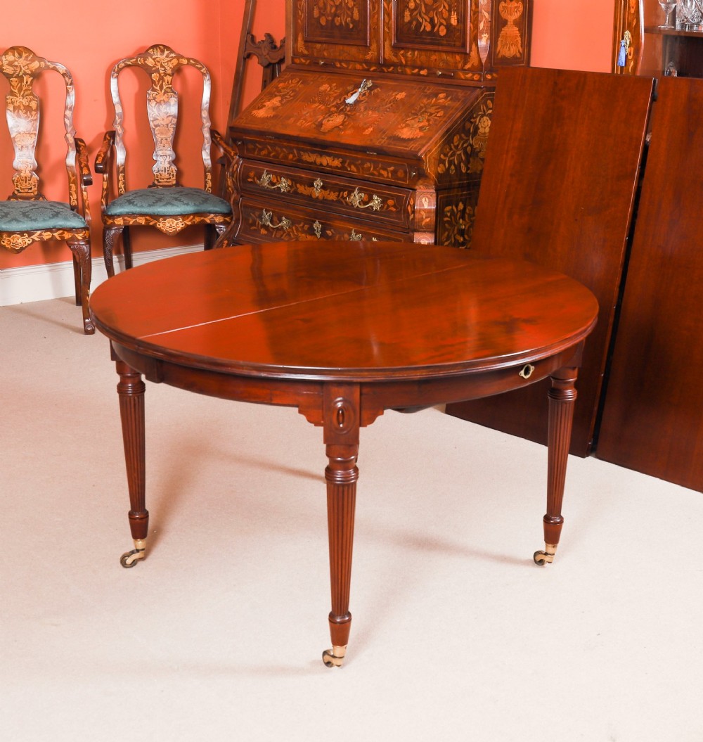 An antique Victorian flame mahogany extending dining table with fluted tapering legs set on brass castors. View IX