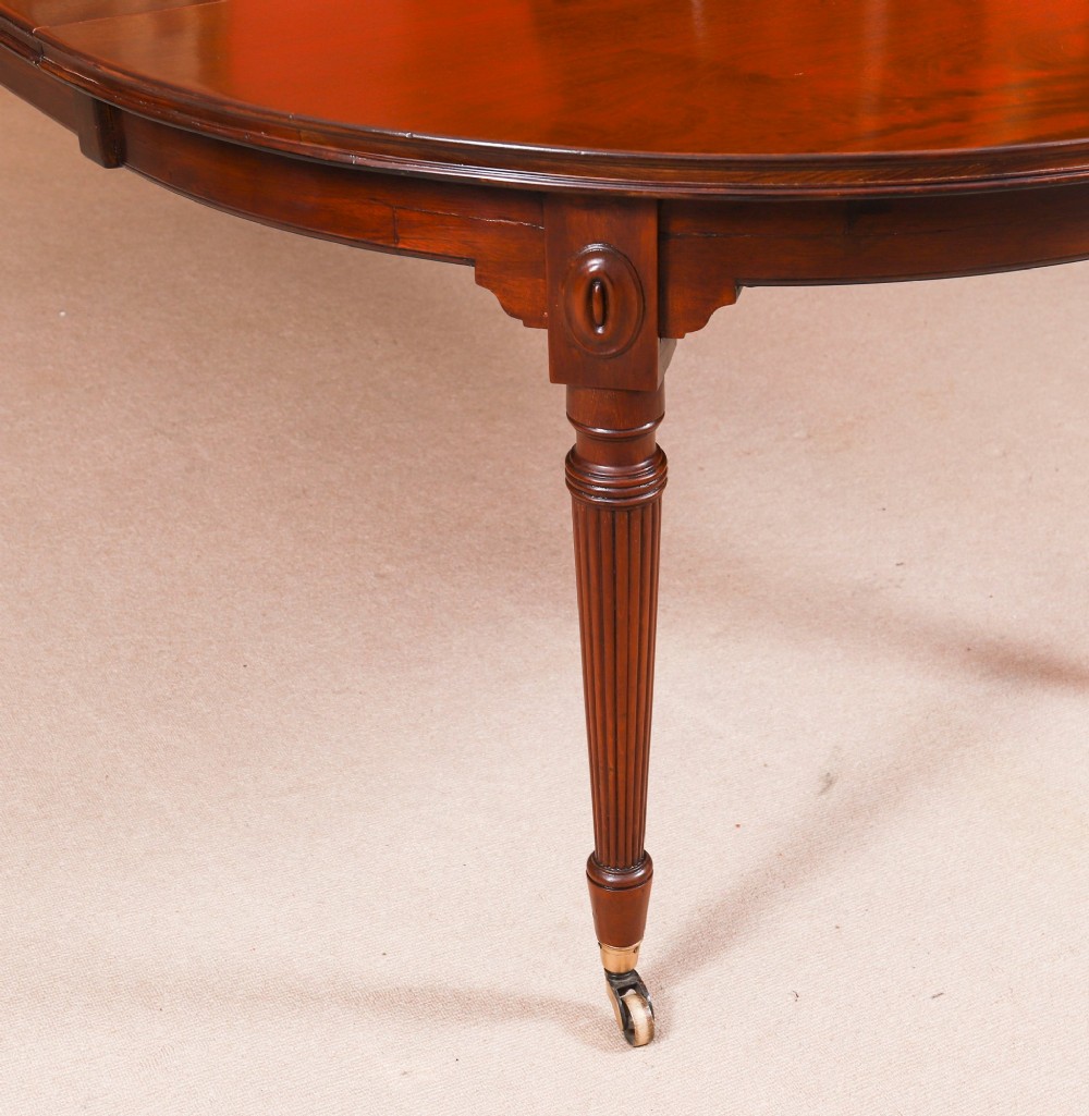 An antique Victorian flame mahogany extending dining table with fluted tapering legs set on brass castors. View XIII