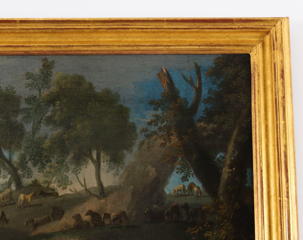 A 17th-century Italian oil painting on board depicting figures and livestock gathered at a well, set within a landscape and surrounded by a moulded gold frame. View V