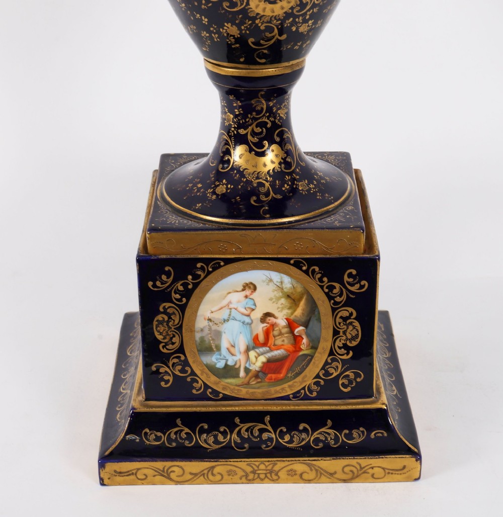 A pair of large 19th-century cobalt blue porcelain vases on matching square pedestals, featuring gilt scrollwork and hand-painted classical mythological scenes. View IV