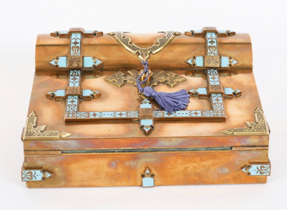 A Victorian gilt brass and turquoise champleve enamel writing slope featuring a domed upper compartment, a sloped front lid, and a key with a purple tassel in the lock. View V