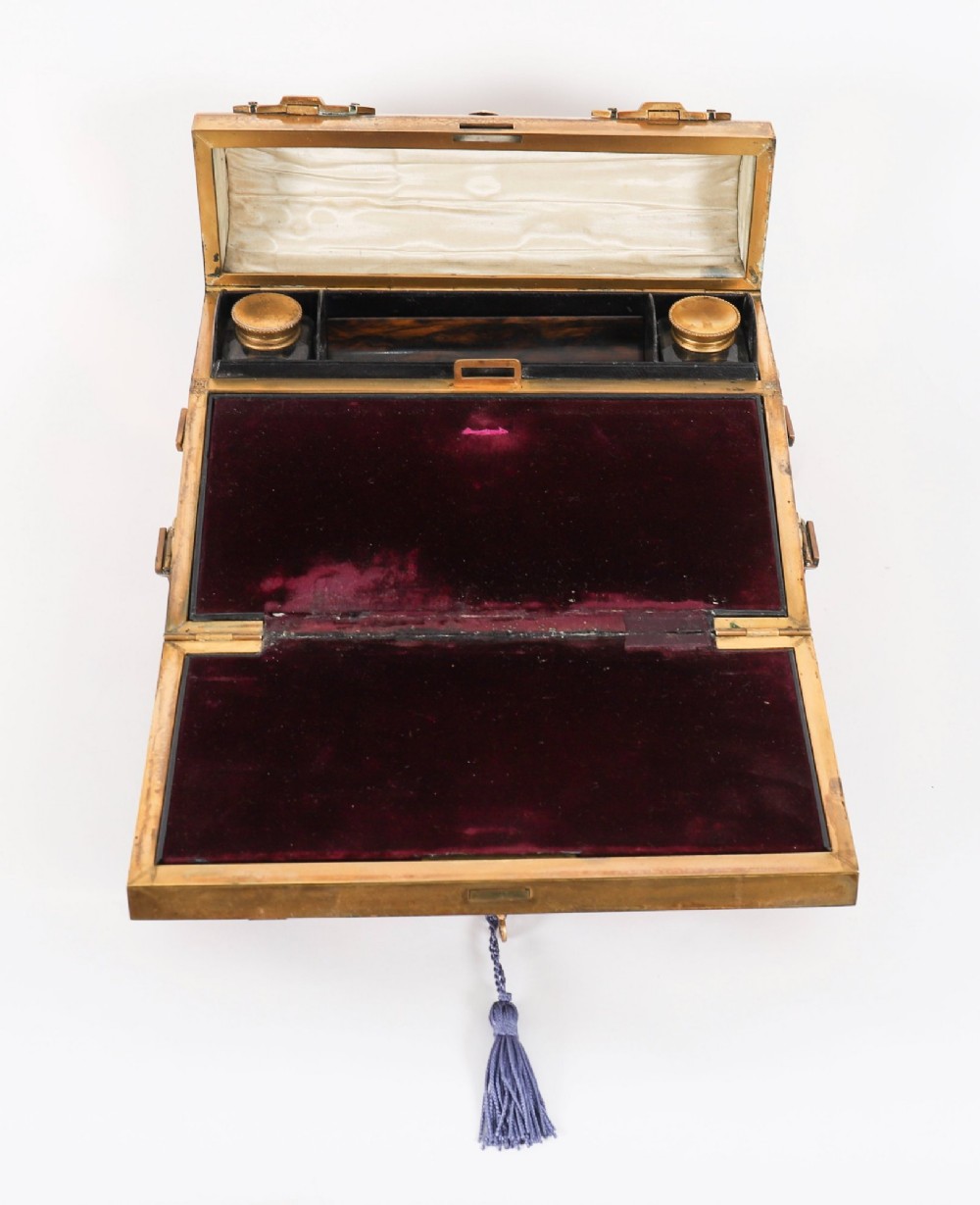 A Victorian gilt brass and turquoise champleve enamel writing slope featuring a domed upper compartment, a sloped front lid, and a key with a purple tassel in the lock. View VIII