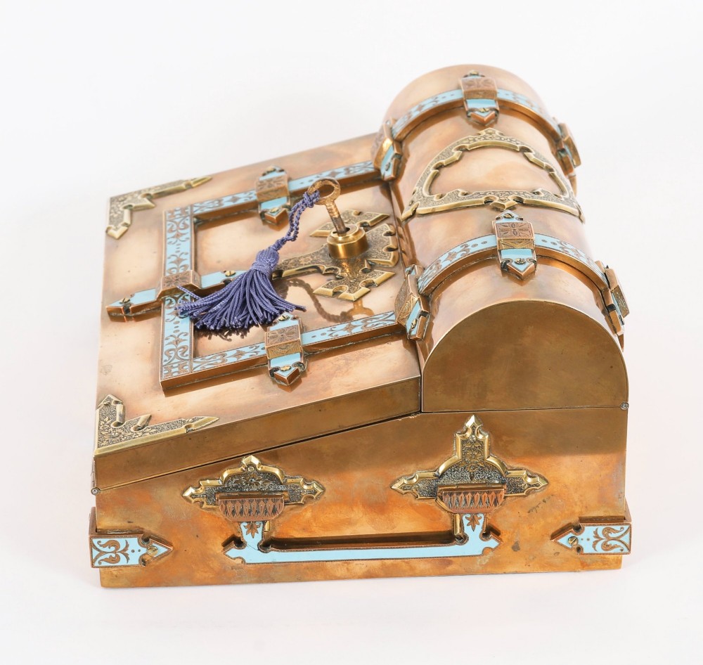 A Victorian gilt brass and turquoise champleve enamel writing slope featuring a domed upper compartment, a sloped front lid, and a key with a purple tassel in the lock. View XI