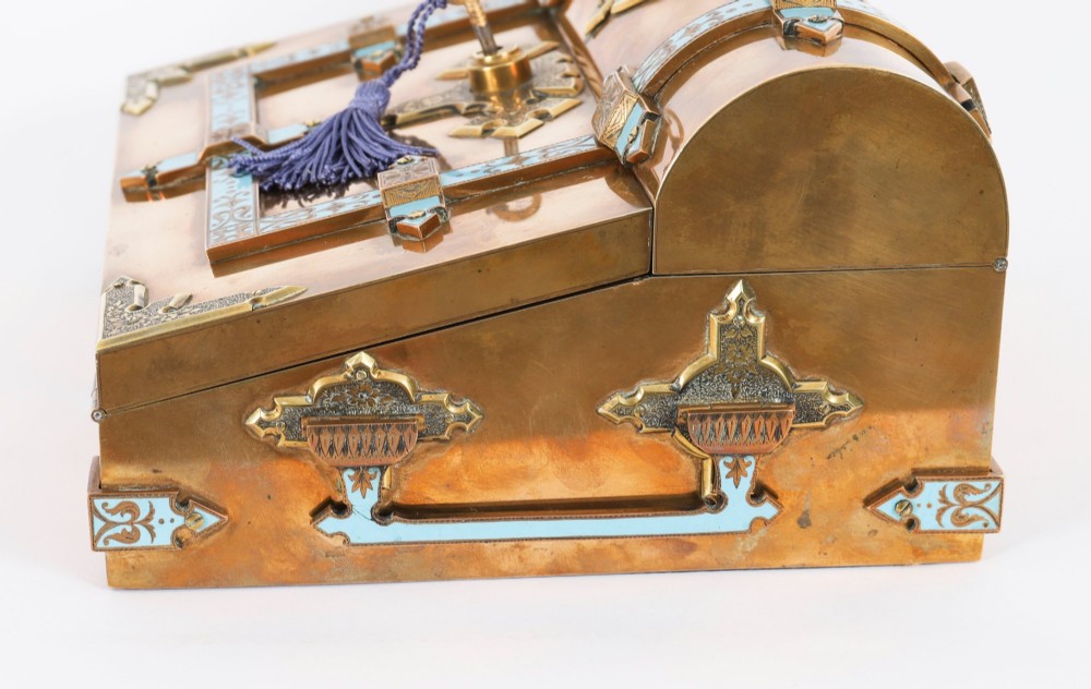 A Victorian gilt brass and turquoise champleve enamel writing slope featuring a domed upper compartment, a sloped front lid, and a key with a purple tassel in the lock. View XII