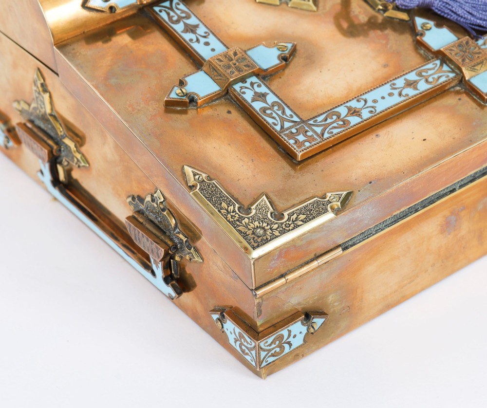 A Victorian gilt brass and turquoise champleve enamel writing slope featuring a domed upper compartment, a sloped front lid, and a key with a purple tassel in the lock. View XIV