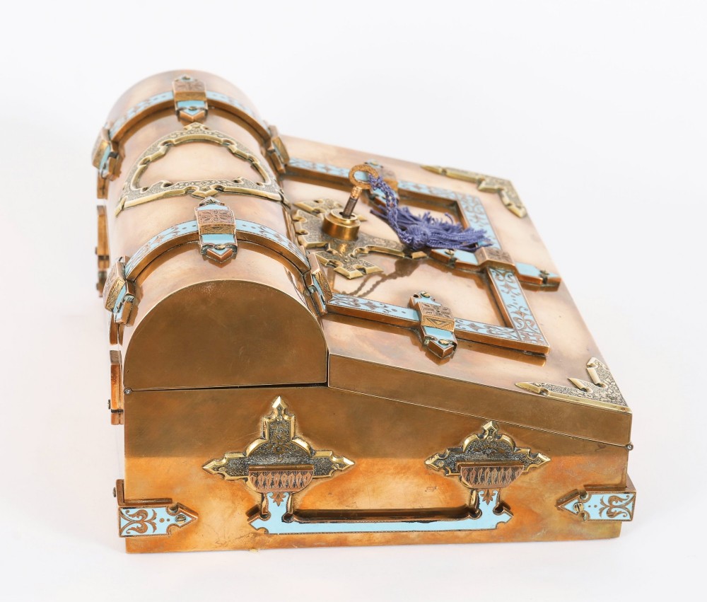 A Victorian gilt brass and turquoise champleve enamel writing slope featuring a domed upper compartment, a sloped front lid, and a key with a purple tassel in the lock. View XV