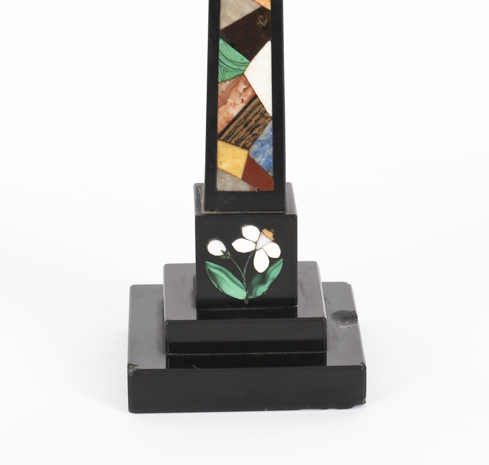 A pair of antique black marble obelisks featuring colourful geometric stone inlays along the shaft and floral inlaid detail on stepped square bases. View VI
