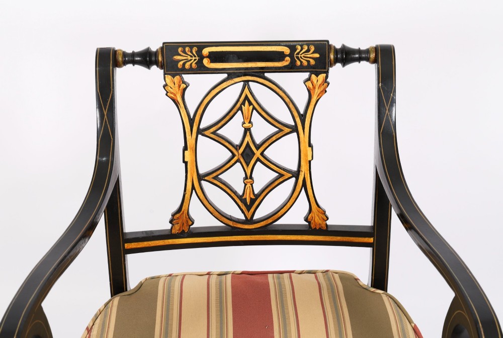 A set of ten black painted Regency Revival armchairs with parcel-gilt details, pierced splat backs, turned front legs, and striped fabric seat cushions. View XII