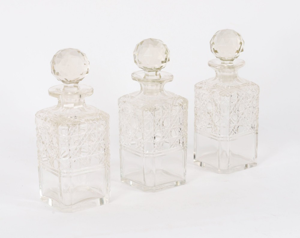 A 19th-century Victorian figured oak three-bottle tantalus open to reveal three cut glass decanters, a fitted cribbage board, and a drop-front drawer containing a silver-plated tray and playing cards. View XIII
