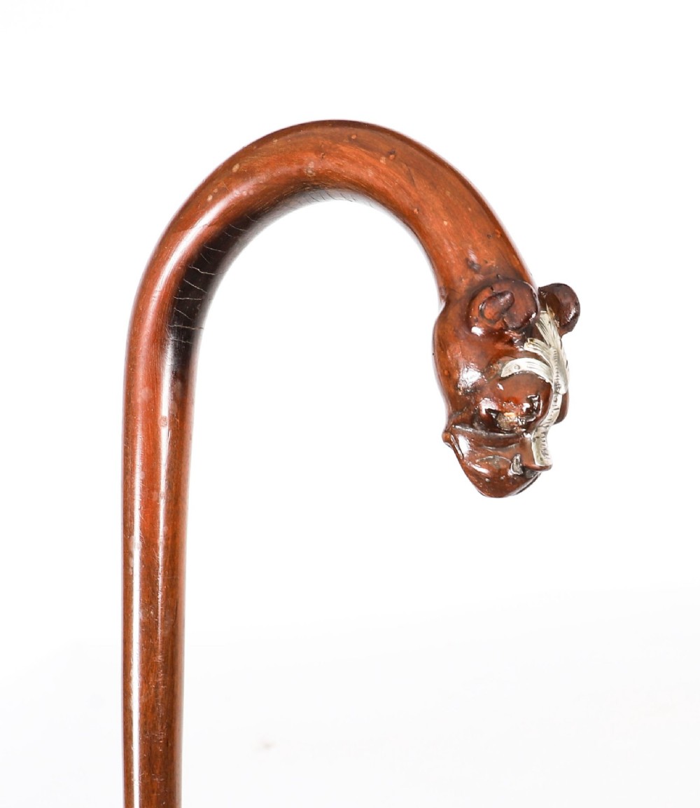 An antique dark wood walking stick featuring a curved crook handle carved into the detailed head of a boxer dog. View IX