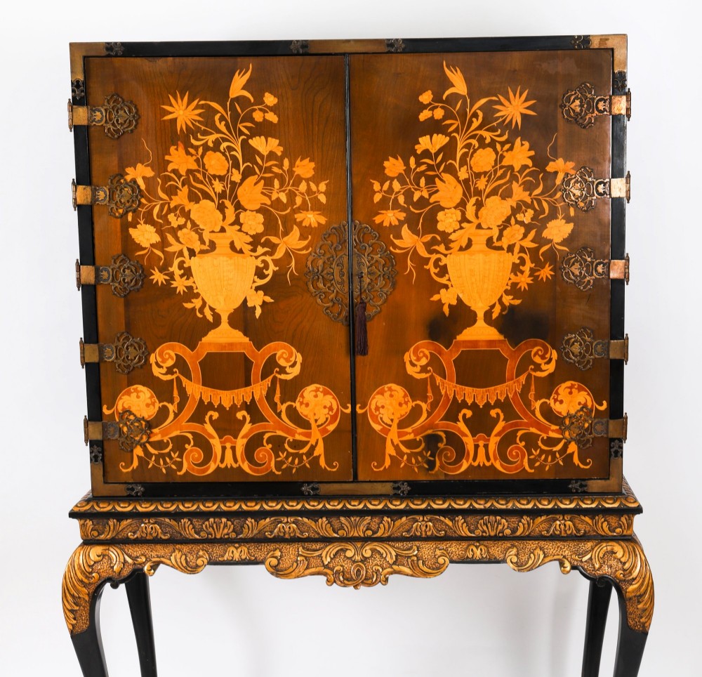 A black lacquered and inlaid wooden cocktail cabinet featuring ornate floral marquetry and decorative brass straps, resting on a carved gilded stand with cabriole legs. View V