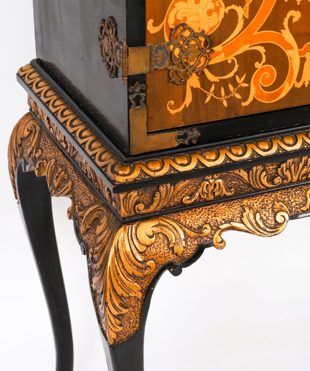 A black lacquered and inlaid wooden cocktail cabinet featuring ornate floral marquetry and decorative brass straps, resting on a carved gilded stand with cabriole legs. View VII