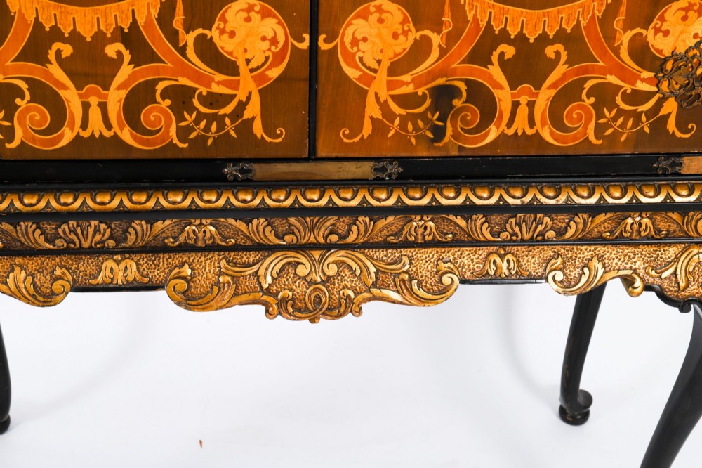 A black lacquered and inlaid wooden cocktail cabinet featuring ornate floral marquetry and decorative brass straps, resting on a carved gilded stand with cabriole legs. View IX