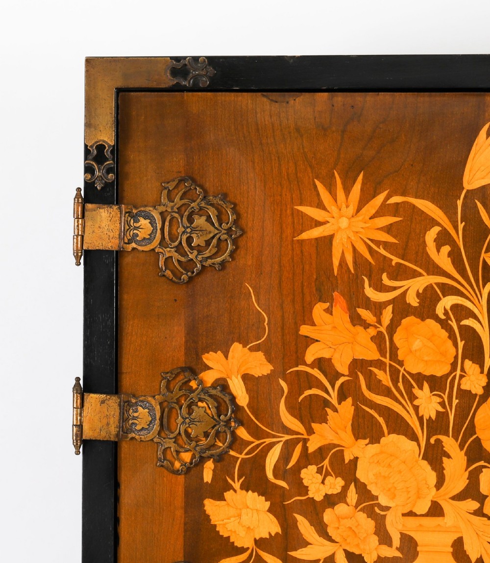 A black lacquered and inlaid wooden cocktail cabinet featuring ornate floral marquetry and decorative brass straps, resting on a carved gilded stand with cabriole legs. View X