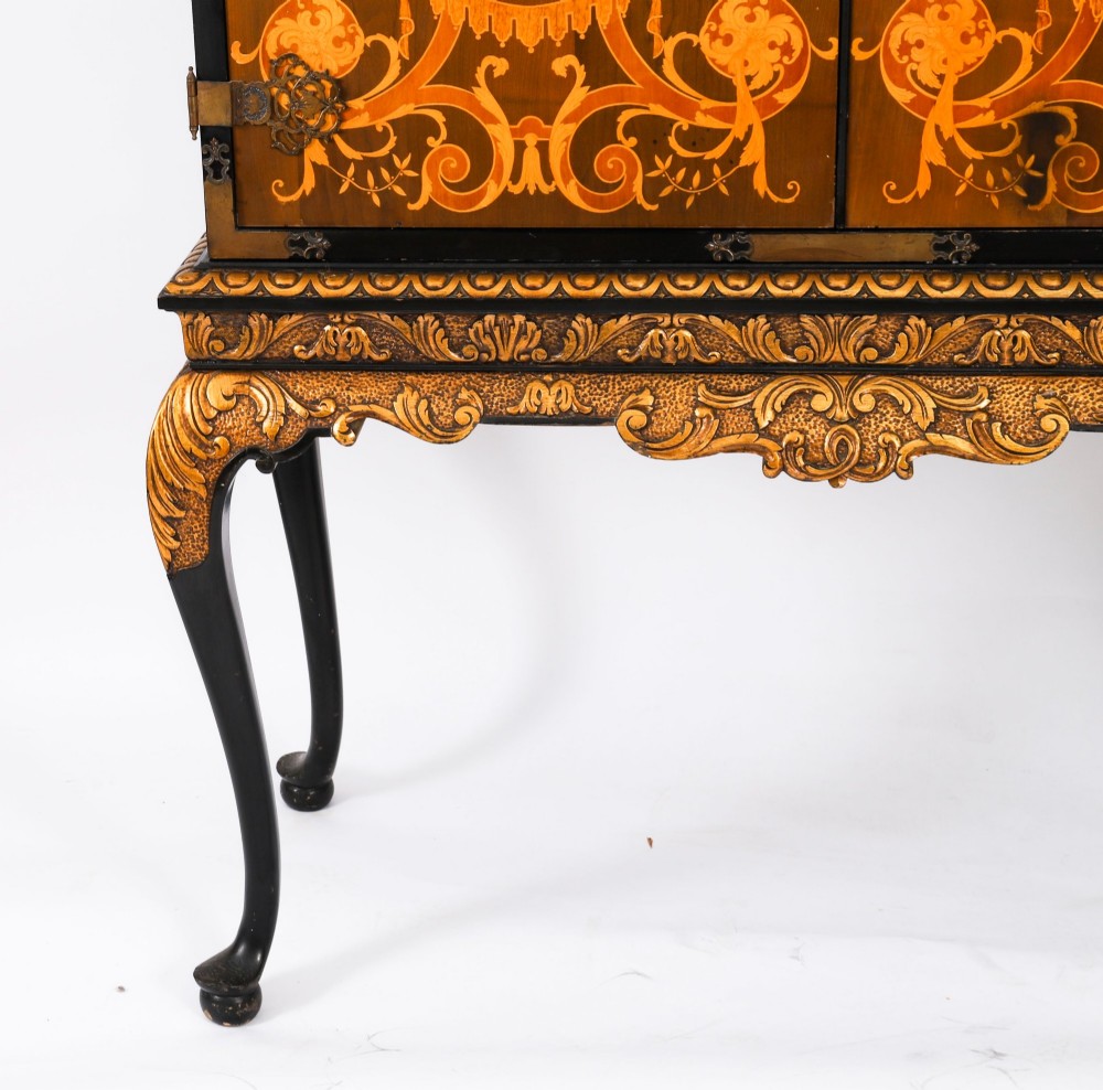 A black lacquered and inlaid wooden cocktail cabinet featuring ornate floral marquetry and decorative brass straps, resting on a carved gilded stand with cabriole legs. View XI