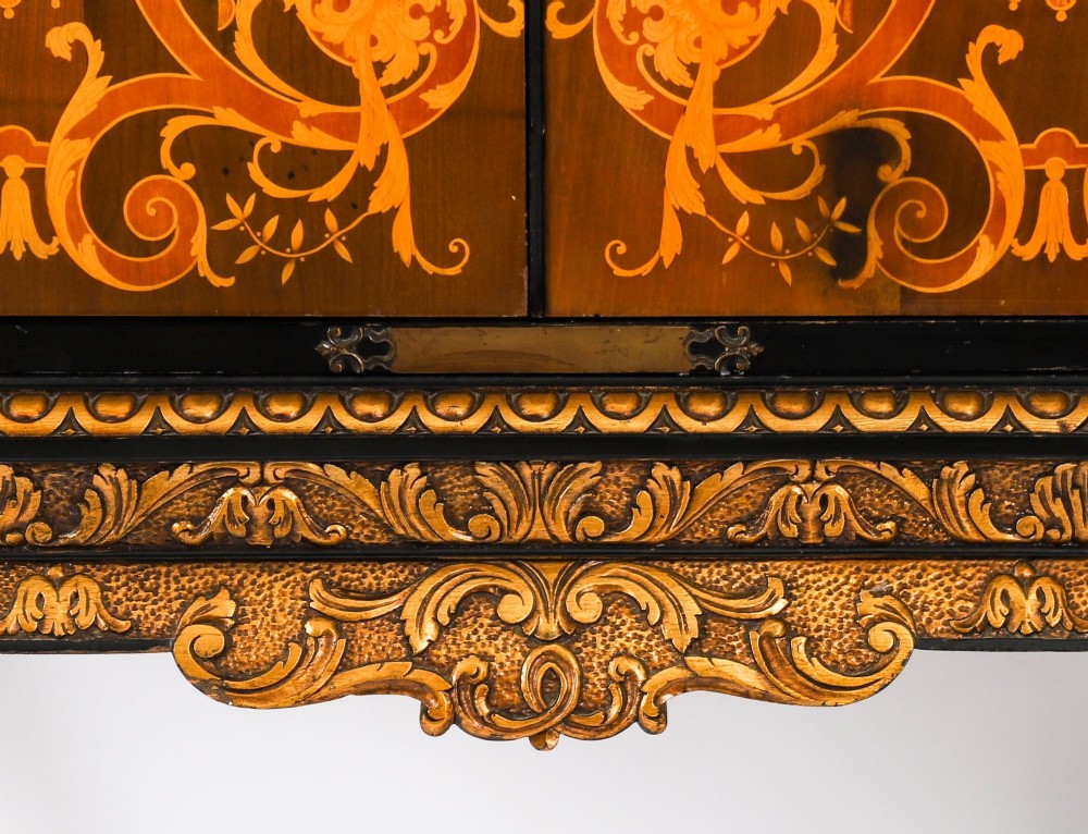 A black lacquered and inlaid wooden cocktail cabinet featuring ornate floral marquetry and decorative brass straps, resting on a carved gilded stand with cabriole legs. View XII