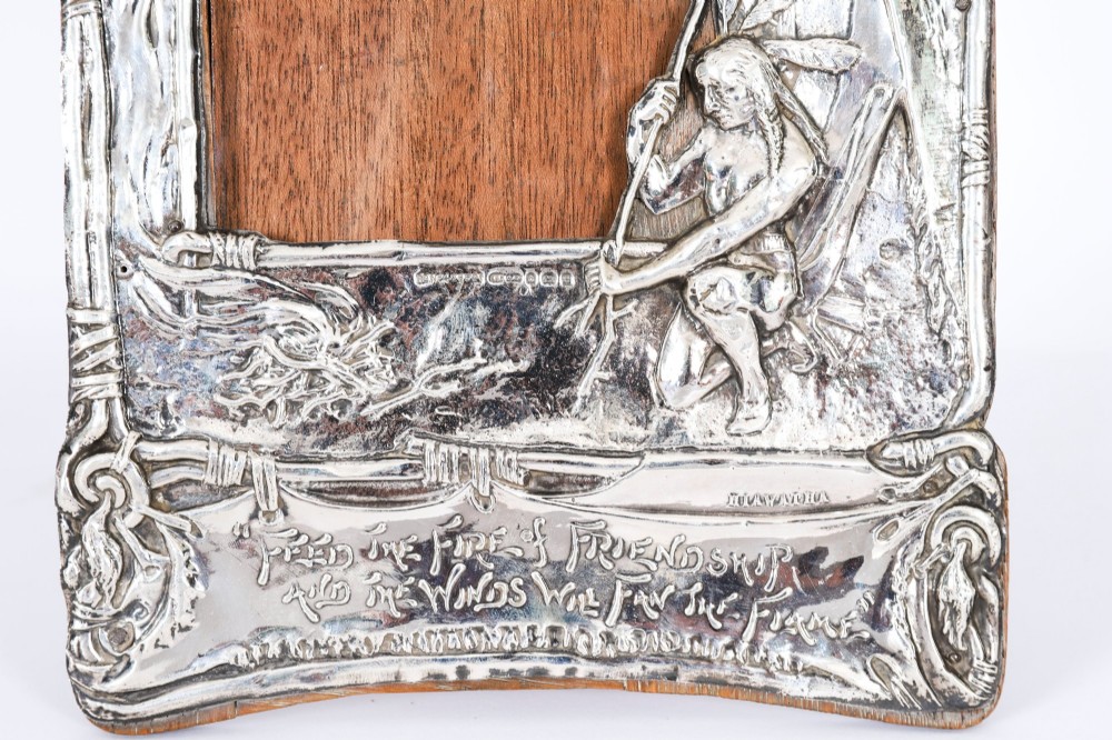 An Edwardian sterling silver picture frame featuring an embossed relief scene of Hiawatha with a wooden backing. View V
