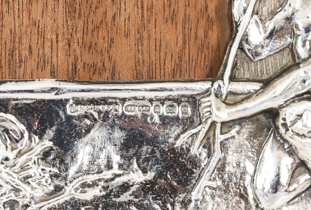 An Edwardian sterling silver picture frame featuring an embossed relief scene of Hiawatha with a wooden backing. View VII