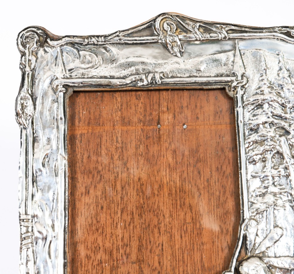 An Edwardian sterling silver picture frame featuring an embossed relief scene of Hiawatha with a wooden backing. View VIII