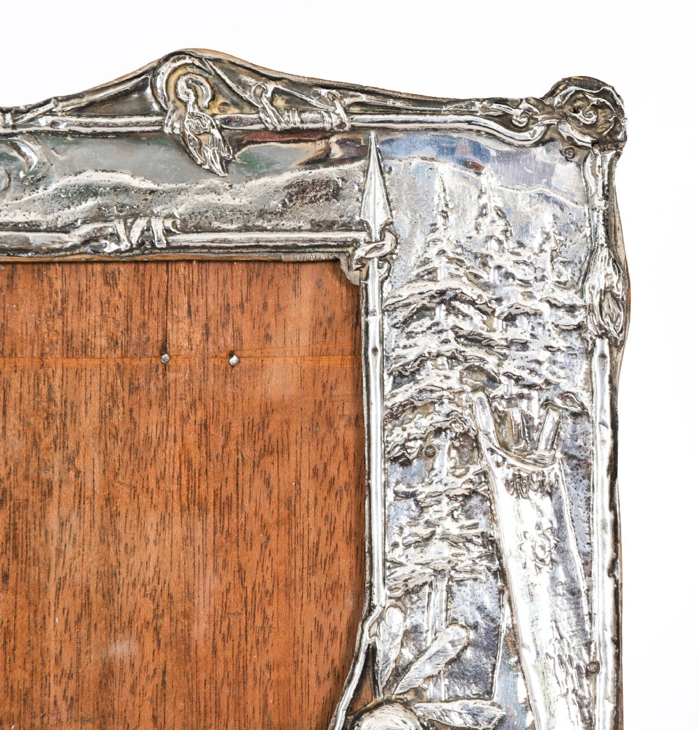 An Edwardian sterling silver picture frame featuring an embossed relief scene of Hiawatha with a wooden backing. View IX