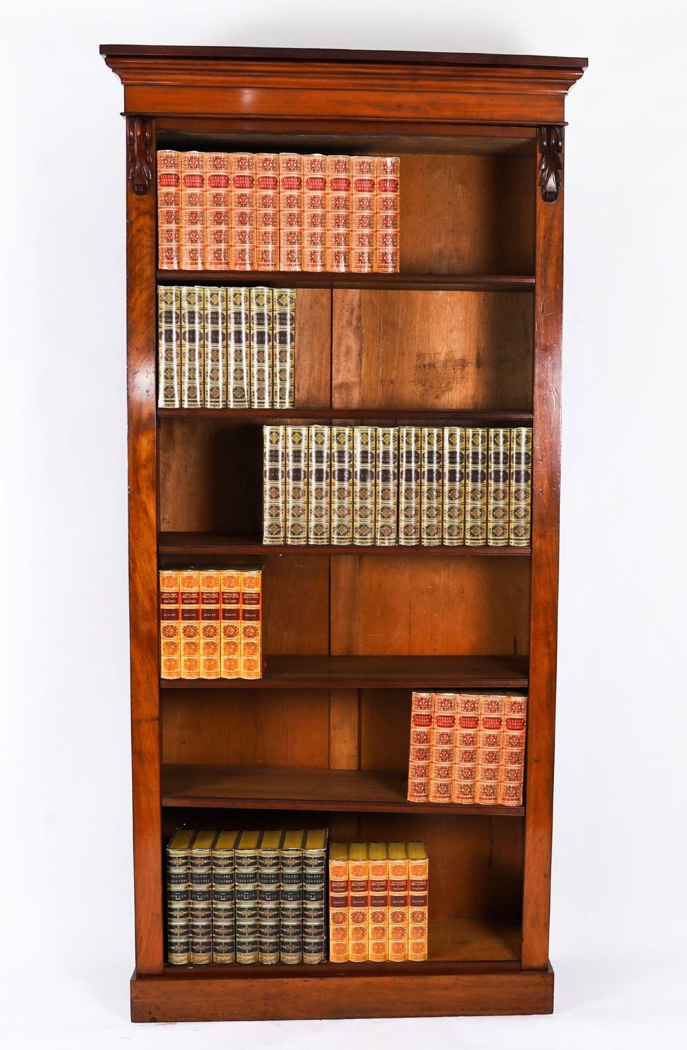 A tall Victorian mahogany open bookcase featuring six tiers of adjustable shelves, flanked by decorative carved corbels under a projected cornice.