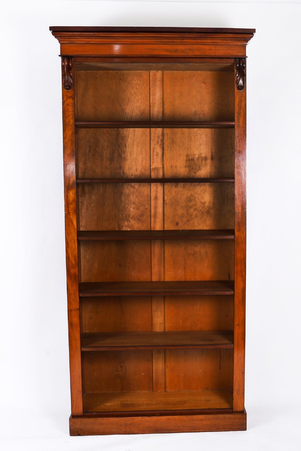 A tall Victorian mahogany open bookcase featuring six tiers of adjustable shelves, flanked by decorative carved corbels under a projected cornice. View III