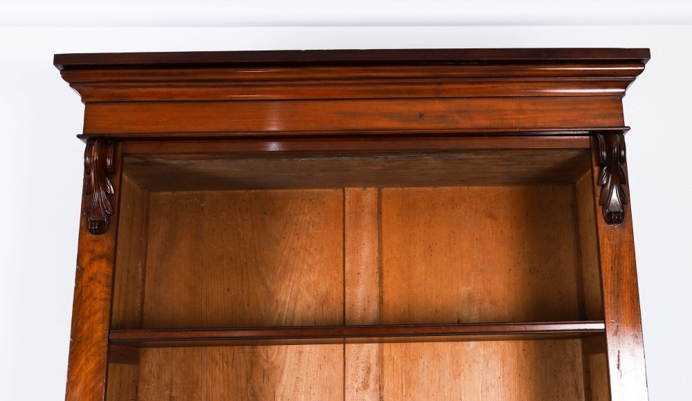 A tall Victorian mahogany open bookcase featuring six tiers of adjustable shelves, flanked by decorative carved corbels under a projected cornice. View V