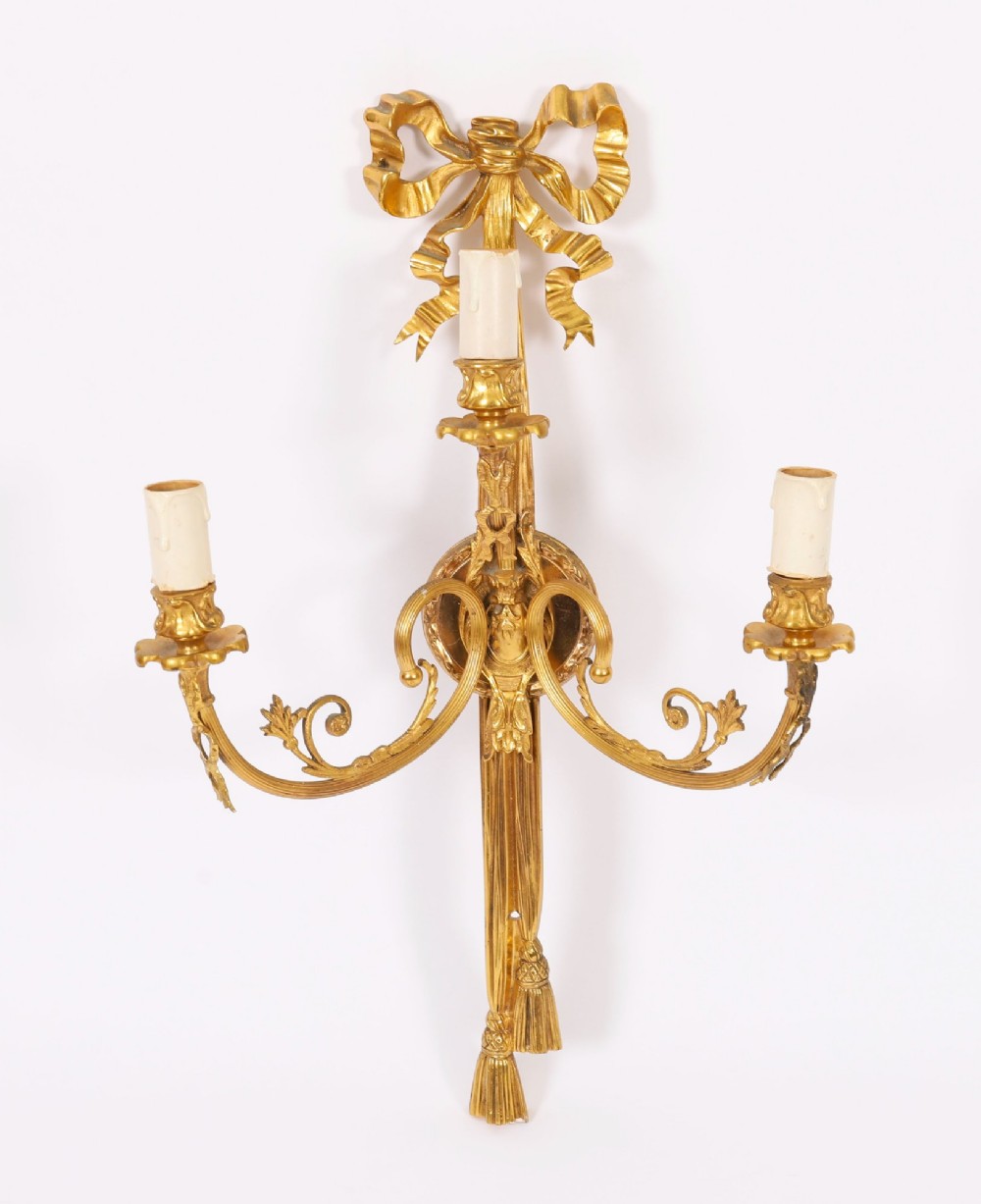 A pair of 19th-century French gilt bronze three-branch wall sconces styled with ribbon bow tops and tassel finials. View II